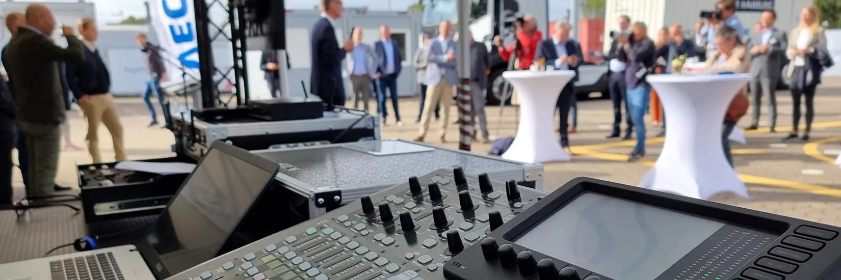 Mischpult im Vordergrund, Gäste eines Kundenevents im Freien